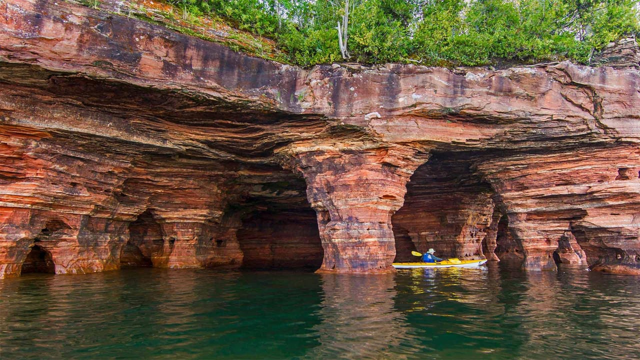 Kayaker exploring sandstone sea caves in Apostle Islands National Lakeshore, USA (© Chuck Haney/Danita Delimont)
