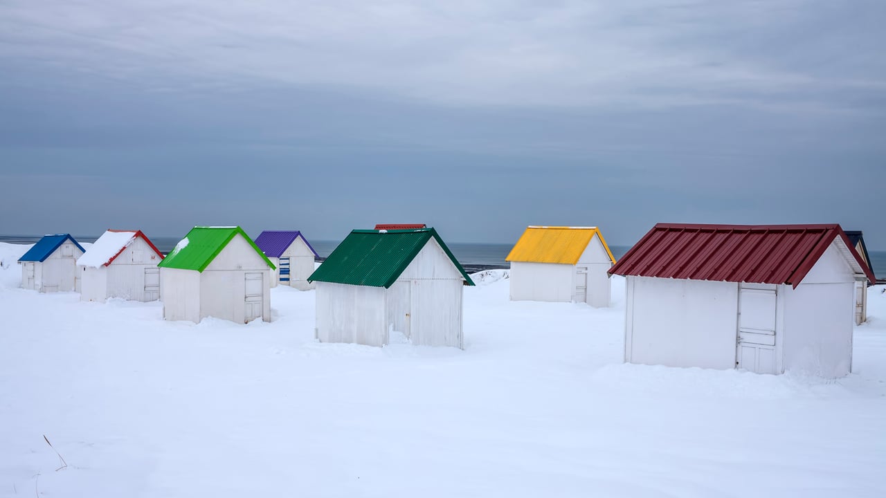 Cabanes aux toits colorés recouvertes de neige à Gouville-sur-Mer, Normandie (© Andia/Getty Images)