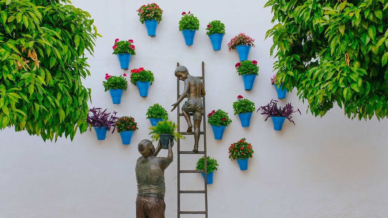 Bronze sculpture of a child and his grandfather caring for plants and flowers in the San Basilio neighborhood of Córdoba, Spain (© David M G/Alamy)