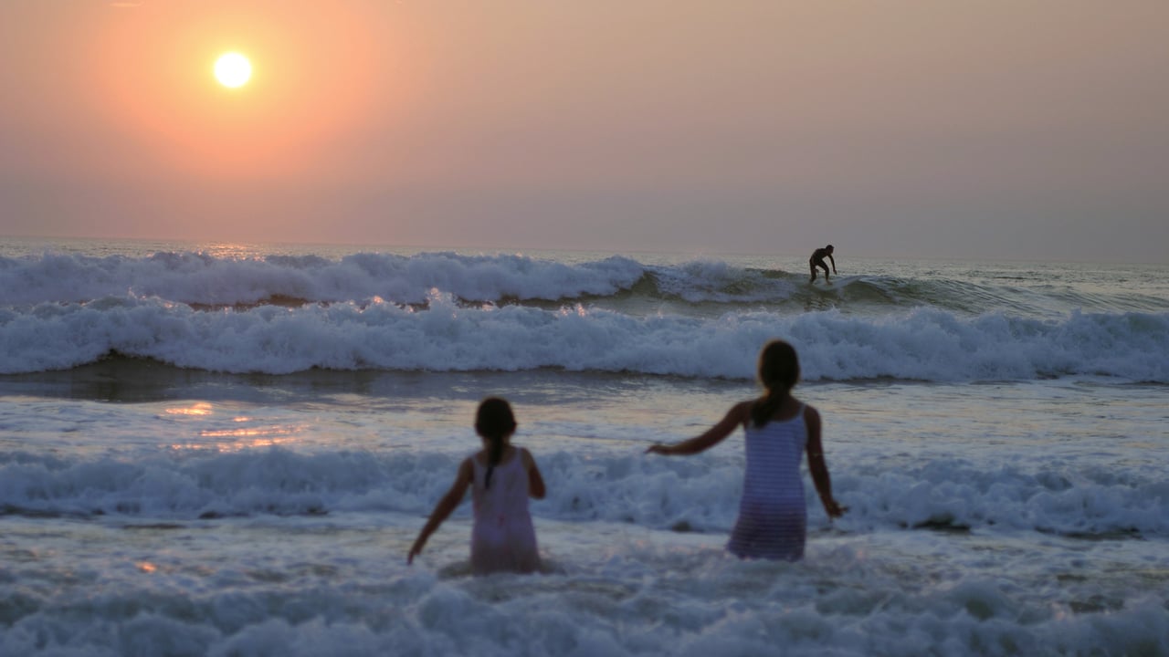 Deux fillettes en pleine baignade devant un coucher de soleil à Lacanau, France (© van hilversum/Alamy Stock Photo)
