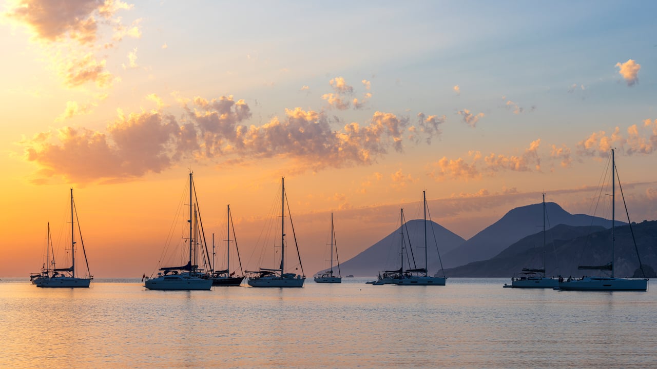 Cielo colorato al tramonto sopra barche a vela ormeggiate, Isole Eolie, Messina, Sicilia, Italia (© Paolo Graziosi/E+/Getty Images)