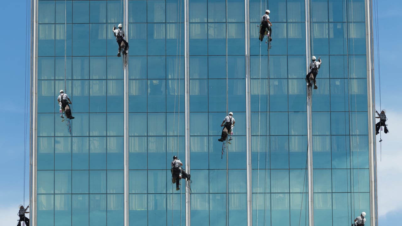 Limpadores de janelas pendurados por cordas, Rio de Janeiro (© Buena Vista Images/Getty Images)