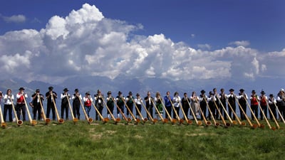 Bing wallpaper July 26, 2019. Alphorn musicians perform during the International Alphorn Festival in Nendaz, Switzerland (© Fabrice Coffrini/Getty Images)