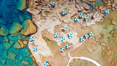 Bing wallpaper July 2, 2020. Aerial view of blue and white parasols on the rocky coast of Rhodes, an island in Greece (© Amazing Aerial Agency/Offset by Shutterstock)