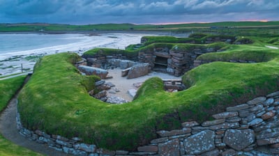 Bing wallpaper July 18, 2021. Stormy sky over Skara Brae, a Neolithic village on the Mainland, Orkney (© Robert Harding World Imagery/Offset)
