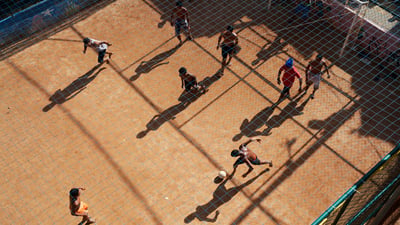 Bing wallpaper July 19, 2026. Vista aérea de jovens jogando futebol em um campo de terra em uma comunidade do Rio de Janeiro, RJ (© Tom Wilde/Getty Images)